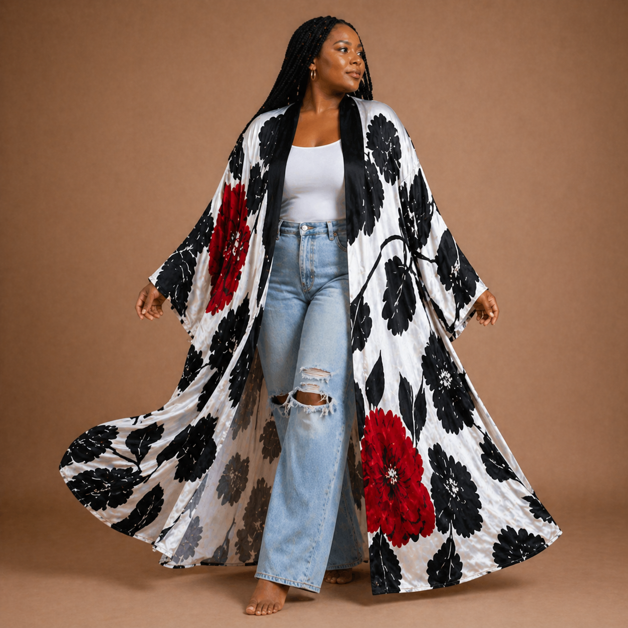 Woman wearing a long, floral-patterned kimono over a white top and jeans on a brown background