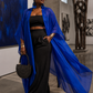Woman in a blue outfit standing in an art gallery with abstract paintings and sculptures. (Blue)