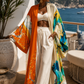 Woman standing on a balcony with a scenic ocean view, wearing a colorful kimono-style garment. (Orange)