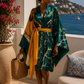 Woman in a green and yellow dress standing on a balcony with ocean (Teal)