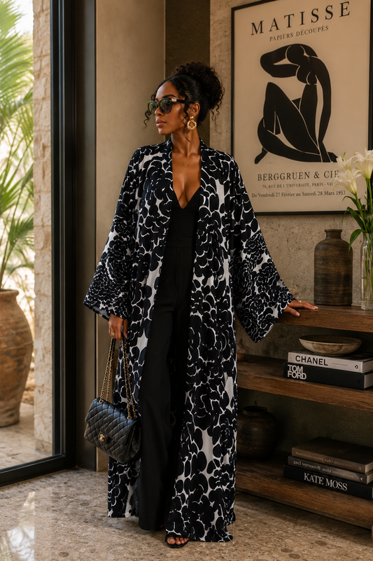 Woman in a black and white patterned coat standing in a room with decor elements.