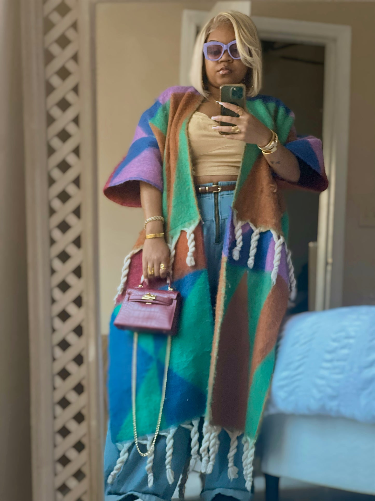 Person wearing a colorful poncho taking a mirror selfie. (Purple)