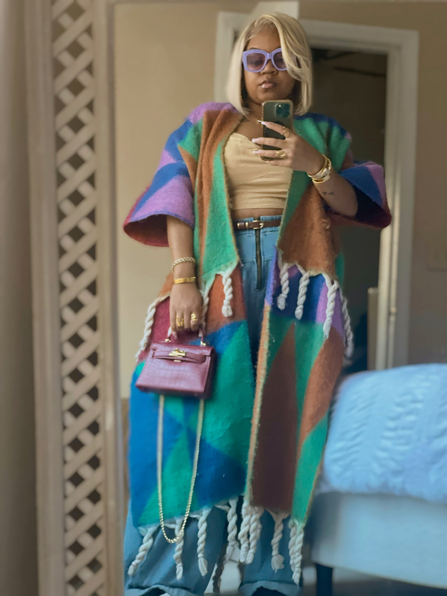 Person wearing a colorful poncho taking a mirror selfie. (Purple)