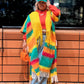 Person wearing a colorful striped shawl and red jacket in an urban setting. (Yellow)