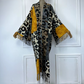 Leopard print poncho with mustard yellow accents on a mannequin against a white paneled wall. (Yellow)