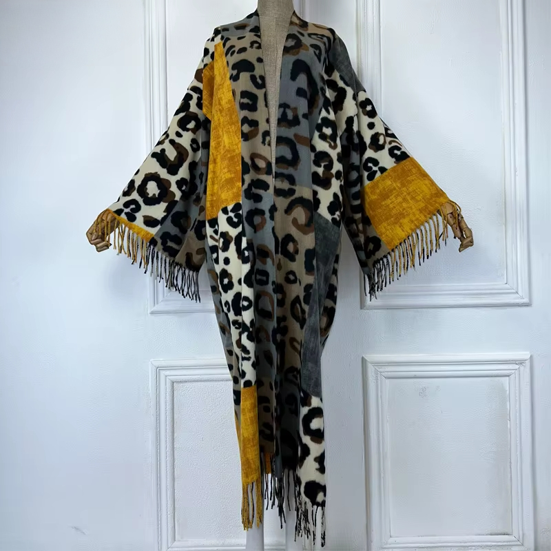 Leopard print poncho with mustard yellow accents on a mannequin against a white paneled wall. (Yellow)