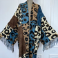 Leopard print shawl with fringes draped over a mannequin against a white wall. (Blue)