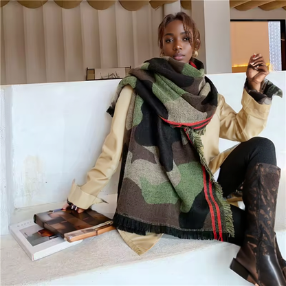Woman sitting on a couch wearing a large green and brown patterned scarf. (Camo)