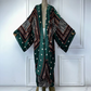 Mannequin wearing a patterned kimono against a white paneled wall. (Green)