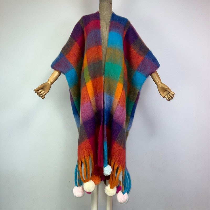 Colorful striped poncho with tassels on a mannequin against a plain background